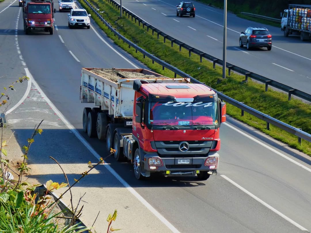 Tracto camión con tolva transportando áridos en carretera