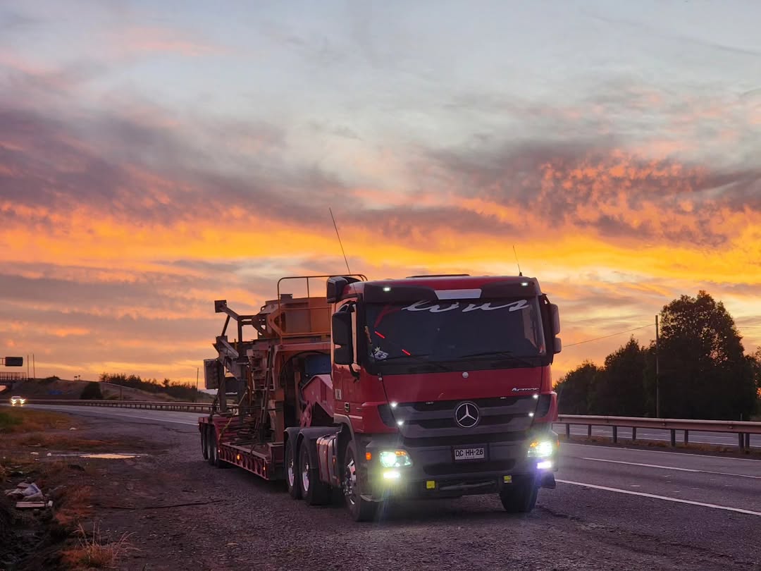 Camión de Transportes Flores trasladando maquinaria al atardecer
