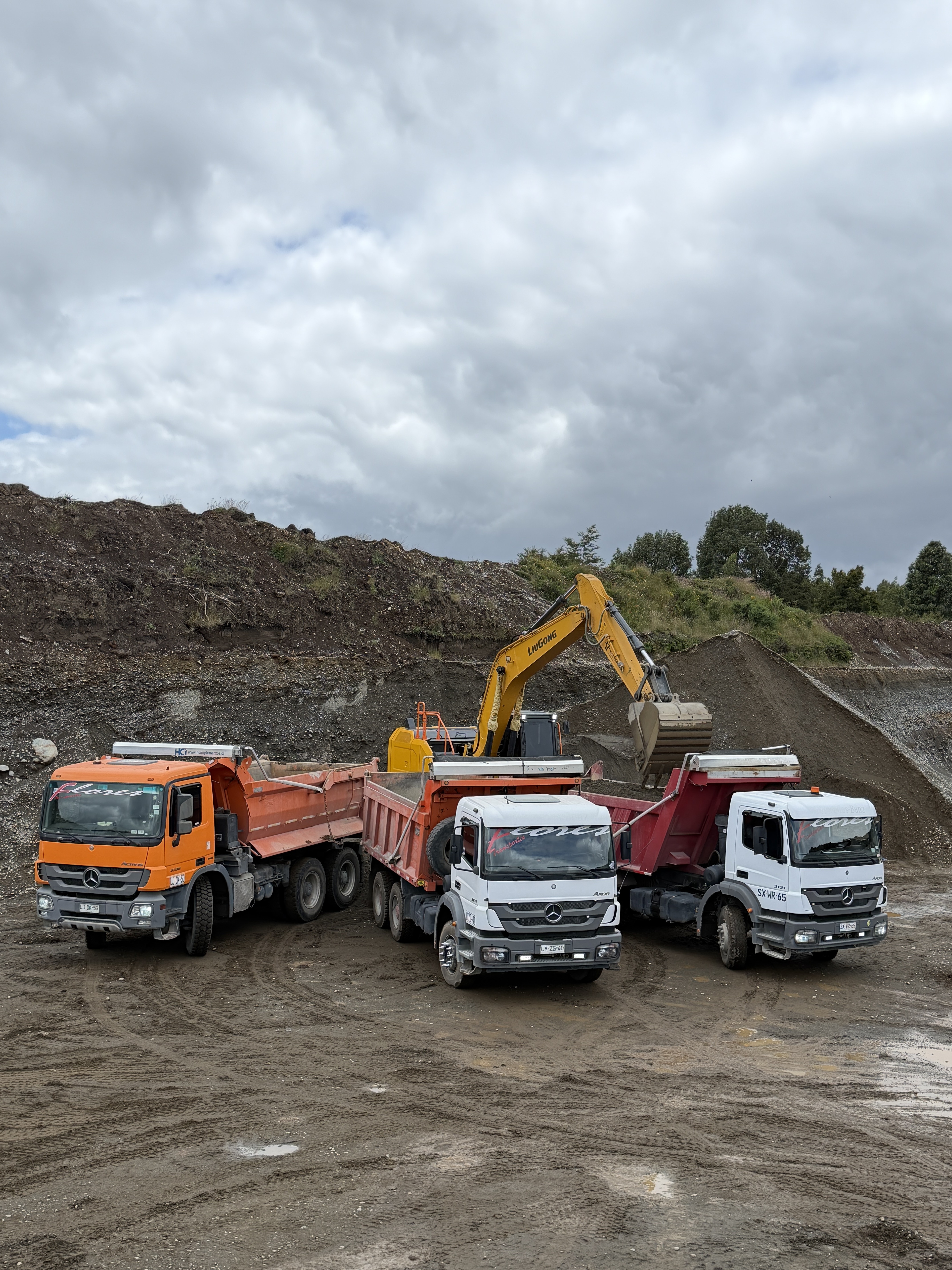 Camiones tolva y excavadora de Transportes Flores cargando áridos