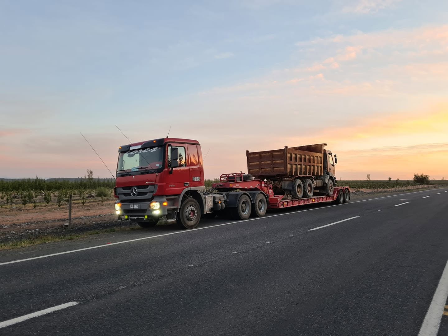Camión cama baja de Transportes Flores trasladando maquinaria pesada