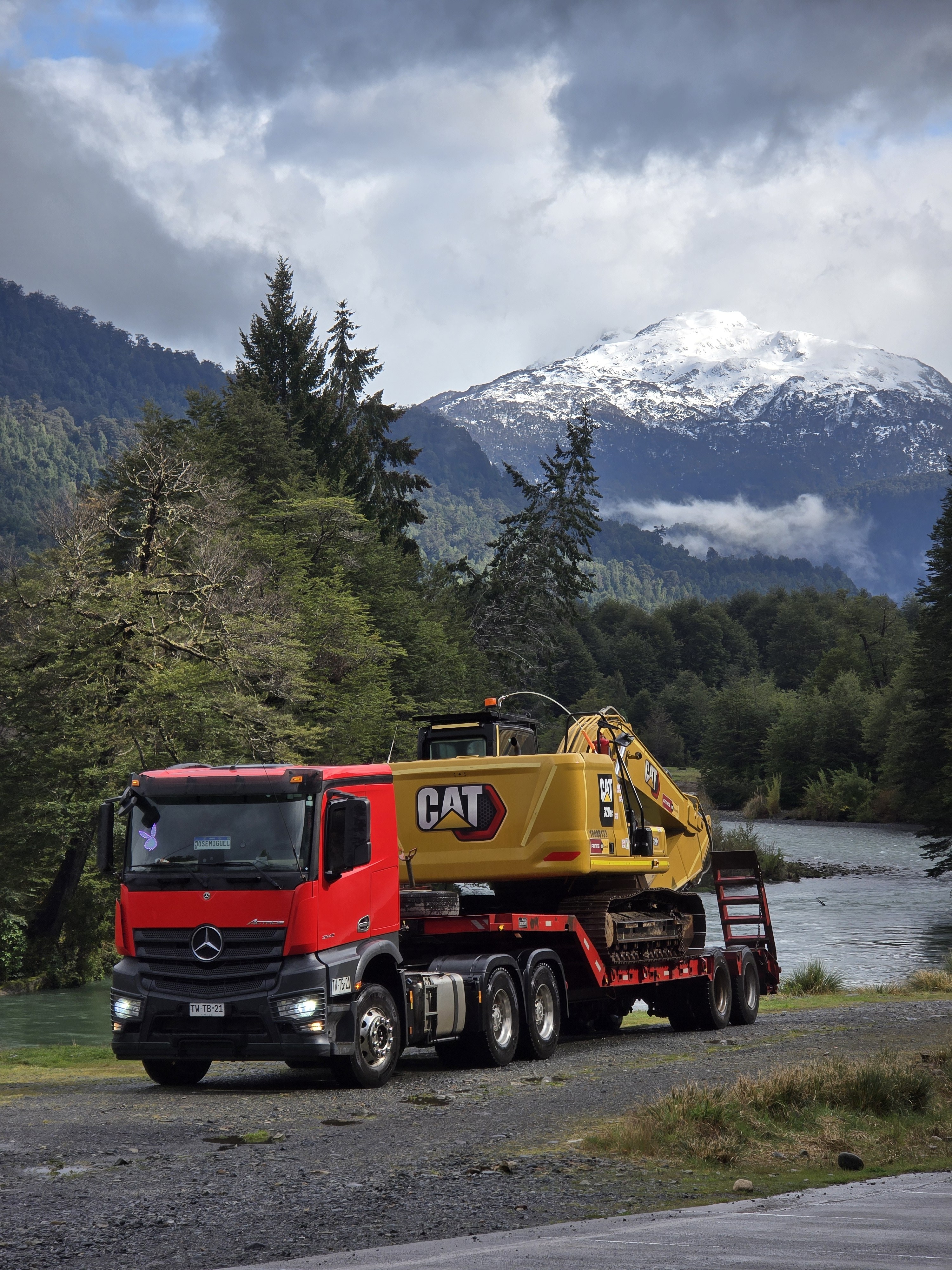 Camión cama baja de Transportes Flores trasladando excavadora en cordillera