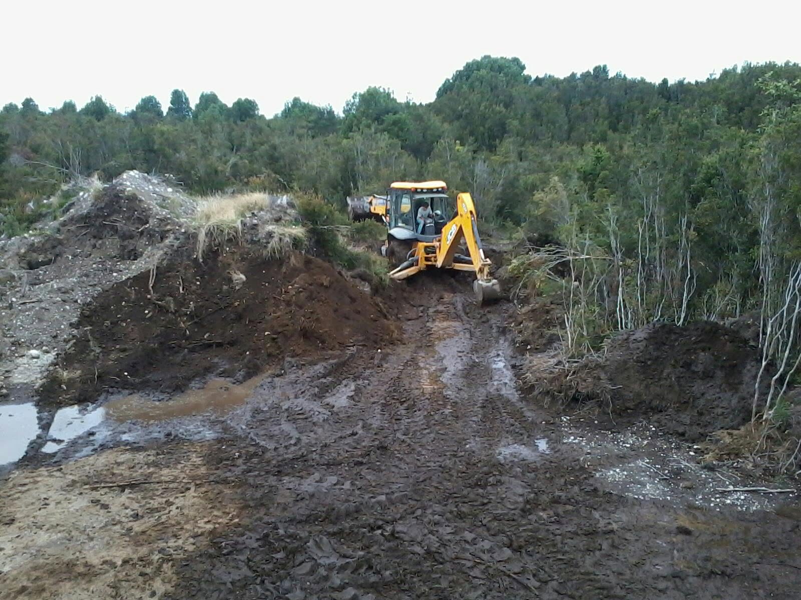 Retroexcavadora abriendo acceso en terreno para faena de Transportes Flores